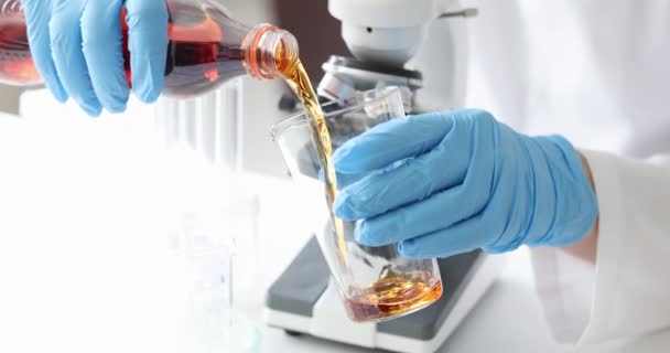 手袋を着用した科学者は ボトルから茶色の液体を実験室のガラスビーカーに注ぐ 研究室のコンセプトにおける飲料研究 — ストック動画