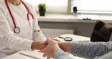 Dost canlısı hasta klinikte doktorla el sıkışıyor. Yakın çekim 4K film ağır çekim. İyileşme konsepti için hasta minnettarlığı