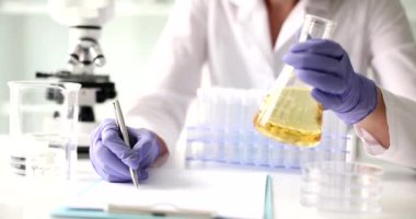 Bilim adamı, mataradaki saydam sarı sıvıyı laboratuvar testine tabi tutuyor. Kozmetik yağların kimyasal uzmanlığı