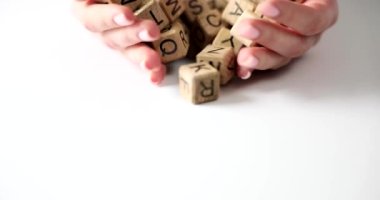 Kadın elleri bir yığın tahta küpü mektupla tutuyor. Eğitim, yaratıcılık ve öğrenme dilleri