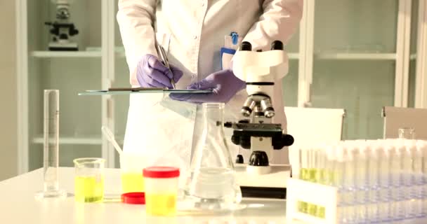 Asisten Laboratorium Dengan Sampel Urin Untuk Analisis Menulis Laporan Medis — Stok Video
