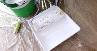 Kapalı mekanda çalışan erkek eller bigudi kullanıyor. Duvarları boyamaya ve kaliteli silindir seçmeye hazırlanılıyor