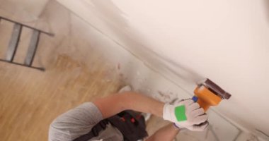 Ev yapım sıva makinesi duvarın yüzeyini öğütücüyle kaplıyor. Duvar onarımı ve resim hazırlığı