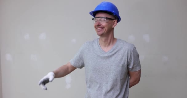 戴着头盔微笑的男性建筑工人的画像与墙壁的修补手指点点 优质家居及办公室翻新服务 — 图库视频影像