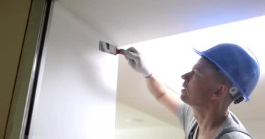 Male builder painting wall white with brush 4k movie slow motion. Finishing work in apartments concept