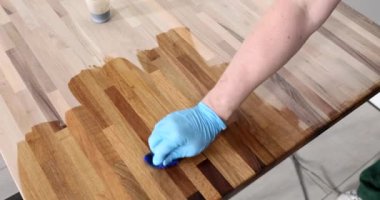 Worker in gloves oiling wooden board closeup 4k movie slow motion. Furniture production concept