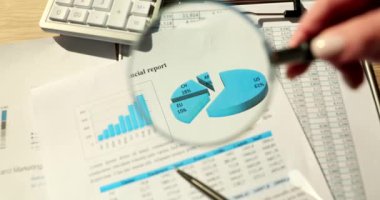 Manager hand holding magnifying glass over graph in financial report closeup 4k movie slow motion. Strategies in business development and work analysis concept