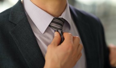 Takım elbiseli şık bir işadamı gömleği yakın çekimde düzeltiyor. Tarz sahibi erkek imajı iş stili kavramı