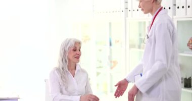 Doktor klinikteki yaşlı kadının elini tutup selamlıyor. Ağır çekimde. Tıp konseptinde kıdemli meslektaşlara yardım etmek