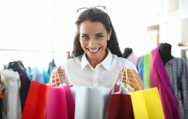 Parlak alışveriş torbalarıyla tatmin olmuş mutlu kadın paketler alıyor ve indirimlerden hoşlanıyor. Gülümseyen kız bayram indirimi için hediye almış.