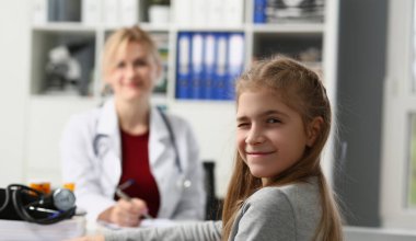 Doktor muayenehanesindeki çocuk portresi kameraya göz kırpıyor. Çocuk doktoru randevusunda hasta numarası yapan çocuk.