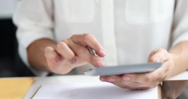 İş kadını hesap makinesine güveniyor ve ofis 4K filminde yavaş çekimde kağıda veri yazıyor. Muhasebe ve muhasebe kavramı