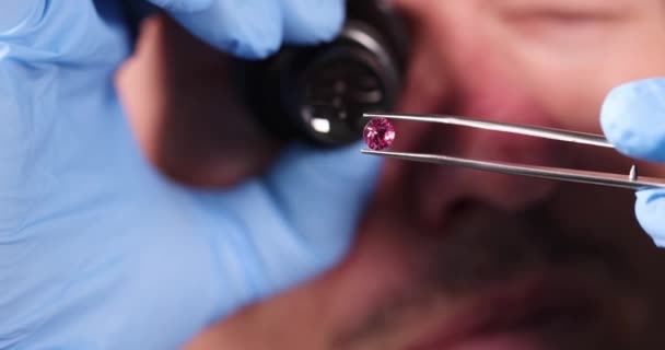 Juwelier Houdt Roze Diamant Handen Kijkt Ernaar Met Vergrootglas Closeup — Stockvideo