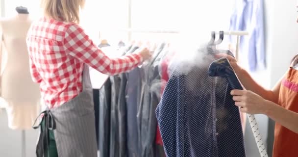 テーラーショップ4K映画スローモーションでスチーマーを使用した女性のシームレスアイロンシャツ ドライクリーニング服のコンセプト — ストック動画