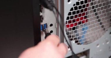Adam eli USB kablosunu bilgisayar bağlantısına sokuyor. 4K 'lık filmi yavaş çekimde kapatıyor. Bilgisayar donanımı konsepti montajı