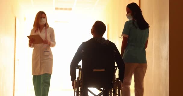 Sjuksköterska Promenader Med Funktionshindrade Man Rullstol Längs Korridoren Kliniken Och — Stockvideo