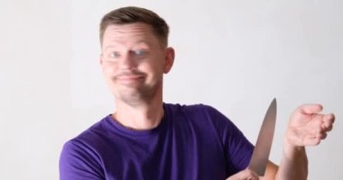Smiling young male shows how to cut vein on arm. Knife games and jokes concept