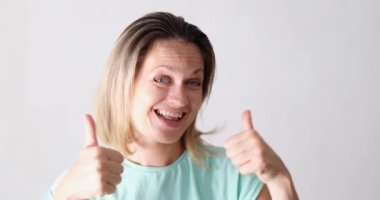 Neşeli, güzel bir kadın baş parmağını kaldırıyor ve dans ediyor. Pozitif duygular ve şans kavramı