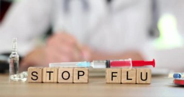 Doktor arka planındaki tahta küplerdeki gribi durduran kelime. Yakın çekim 4K film ağır çekim. Grip önleme aşısı kavramı