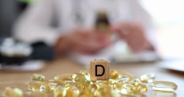 Masanın üzerinde duran D3 vitaminlerinden oluşan bir sürü sarı jelatin kapsülü var. 4K yavaş çekim. Raşitizm önleme kavramı