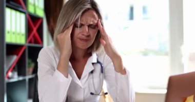 Kadın doktor klinikteki şakaklara masaj yapıyor. Ağır çekimde. Tıp işçilerinin duygusal çöküntüsü konsepti