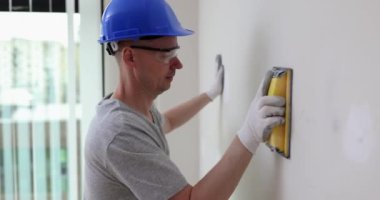 Erkek müteahhit duvarları çimento ve alçı 4K film yavaş çekimde kazıyıcı ile temizliyor. İşlerin bitirilmesi daire yenileme konsepti