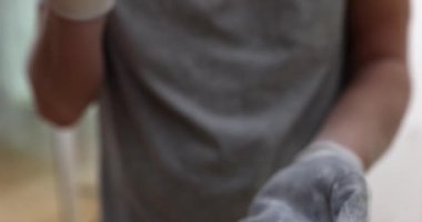 Koruyucu eldivenler giymiş bir inşaatçı ellerini çırpıyor. Toz bulutu yakın çekim 4K yavaş çekimde uçuyor. Alçı döşeme konsepti bitiriliyor