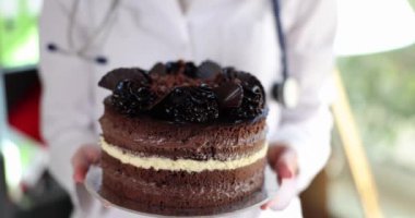 Doctor nutritionist holding in hands delicious appetizing cake closeup 4k movie slow motion. Medical worker day concept