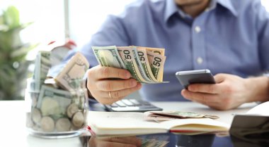 Erkek el banknot ve cep telefonu tutan paketi bazı hesaplama lar yaparak gelecekteki giderleri closeup kavramı planlama