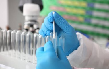 Adli tıp uzmanı, laboratuvar geçmişine karşı adli soruşturma yürütüyor. Elinde DNA örneği ve bir test tüpü ile pamuklu bez tutar. Tets babalık kavramı.