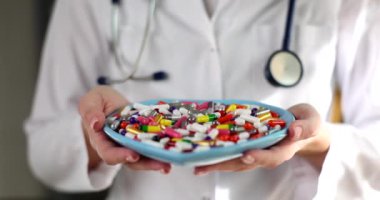 Doktor renkli kapsülleri bir tabakta tutuyor, yakın plan. Beslenme malzemeleri, homeopati tedavisi