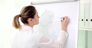 Bir kimyager beyaz bir tahtaya formül yazar, yakın plan. Farmakoloji ve eğitimde yeni bileşenler