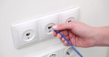 El, duvardaki prizdeki internet kablosunu da içeriyor, yakın plan. Duvar soket bilgisayarı