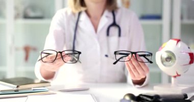 Kadın, yakın plan görüş için bir gözlük modeli gösteriyor. Gözlük çerçevesi seçiyorum, göz doktoru.