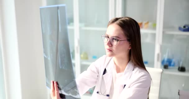 诊所里的一位年轻女医生正在看X光的特写 复杂疾病的诊断 — 图库视频影像