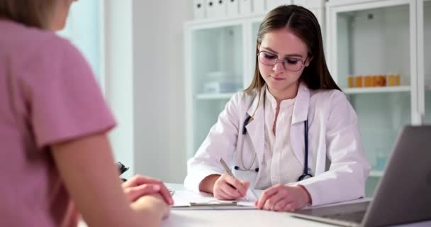 女人是医生 听病人坐在桌旁 诊所会诊 疾病症状 — 图库视频影像