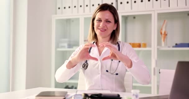 Mujer Feliz Médico Sentado Mesa Muestra Signo Del Corazón Primer — Vídeos de Stock