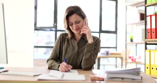 Masanın Ofisindeki Kadın Telefonla Konuşuyor Yakın Plan Bir Yazı Yazıyor — Stok video