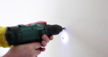 İnşaatçının elleri duvarda tornavidayla bir delik açıyor, yakın plan. Konsept apartman yenileme