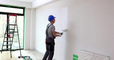 Odadaki müteahhit, uzun menzilli bir mermiyle bir duvarı boyuyor. Konsept ofis onarımı, yavaş çekim