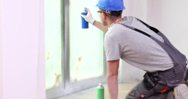 Usta spreyi pencereye boyayla sıkar, yakın plan. Dairedeki pencere çerçevesi güncelleniyor