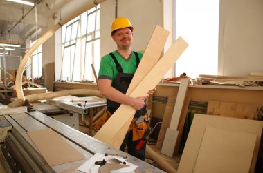 Gülümseyen bir marangoz ahşap plakalar bir inşaat alanında tutarak portresi