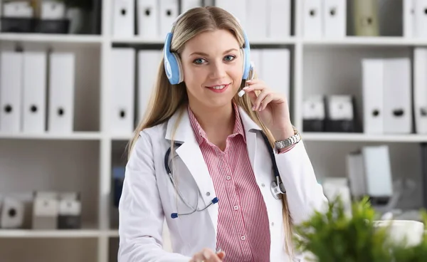 A beautiful feminine blonde doctor talking to patient over wireless headset advises a medical problem the formation of remote education internship callcenter specialist