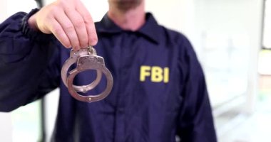 Ajan FBI üniforması elinde kelepçelerle 4K filmi tutuyor. Federal Güvenlik Hizmetleri Konsepti