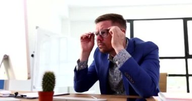 İş adamı bilgisayar ekranının önünde gözlüklerini çıkarıp 4K filminde başını tutuyor. Başarısızlık ve çevrimiçi iş sorunları kavramı
