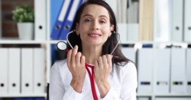 Kadın doktor, klinik 4K filminde ağır çekimde hastaya göz kulak olmak için steteskop takıyor. Sağlık hizmeti kavramı