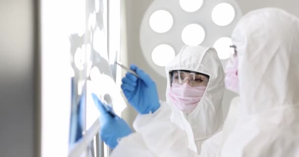 Twee Artsen Beschermende Pakken Maskers Onderzoeken Röntgenfoto Het Laboratorium Coronavirus — Stockvideo