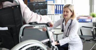 Doktor tekerlekli sandalyedeki kadının diz eklemini nörolojik olarak muayene ediyor. Omurga yaralanması bacak uyuşması konsepti
