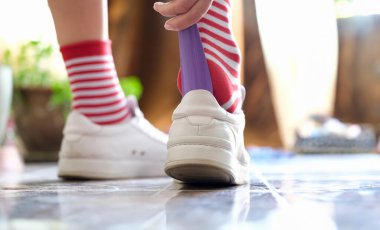 Person puts a shoehorn into sneakers. Rules for dressing shoes concept