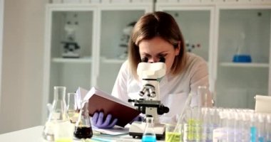 Genç bilim kadını kadın, laboratuarda kitap okuyor. Biyolog laboratuvar araştırması yapıyor.